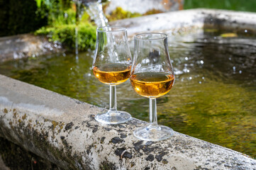 Glasses of strong scotch single malt whisky served on old stone reservoir for water from mountain spring