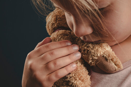 a lonely girl hugs a teddy bear. a lost childhood. an orphan child