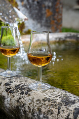 Glasses of strong scotch single malt whisky served on old stone reservoir for water from mountain spring