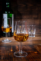Glasses of strong scotch single malt whisky served on dark wooden table in old pub