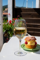 Tarte tropezienne or La Tarte de Saint-Tropez - dessert pastry consisting of filled brioche with cream and fresh berries.and glass of white wine