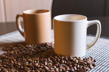 Two mugs of coffee and coffee beans.