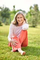 Fototapeta premium Smiling woman barefoot sitting on grass