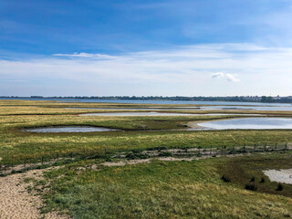 Naturschutzgebiet mit grünen Wiesen in bauem Wasser im Hintergrund