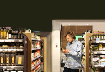 Fototapeta na wymiar Young man shopping in supermarket, reading product information