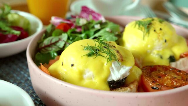 Close-up of Fresh Poached Eggs with Salmon on Baked Muffin with Grilled Vegetable and Salad. Healthy Breakfast in Hotel. Benedict Eggs with Bread and Tomato in Trendy Pink Plate. Fitness Meal.