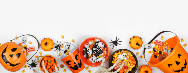Halloween trick or treat bottom border with jack o lantern pails and a variety of candy. Top view...