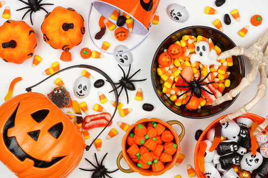 Halloween trick or treat scene with jack o lantern pails and assorted candy. Overhead view on a white background.