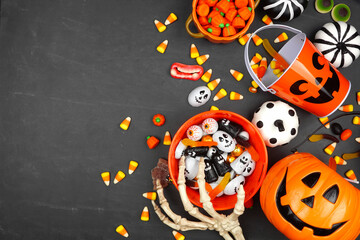 Halloween trick or treat side border with jack o lantern pails and assorted candy. Top view on a...