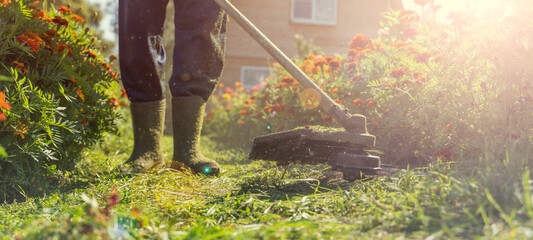 a man mows the lawn with a trimmer m water