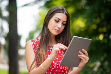Fototapeta premium Woman using a digital tablet in the park