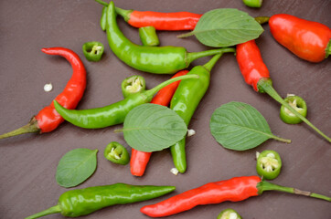closeup the bunch red ripe sliced green chilly with green mint over out of focus brown background.