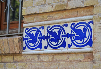 
white ceramic tiles with blue decoration inserted on brick wall