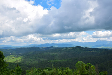 View of the valley from the top of the mountain on a background of several mountains and the sky with clouds