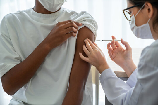Young man visits skillful doctor at hospital for vaccination . Covid 19 and coronavirus vaccination center service concept .