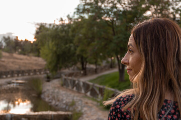 Woman walking in a park with water in an autumn sunset. Selective focus.