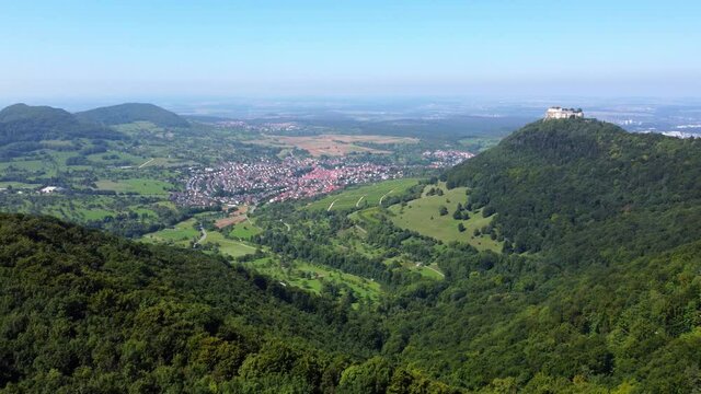 Aerial footage of sideways flight over scenic landscape with forested hills and an old castle (Hohenneuffen) in the Swabian Alps in Southern Germany
