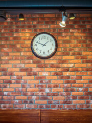 The wall clock hangs on a red-brick wall.
