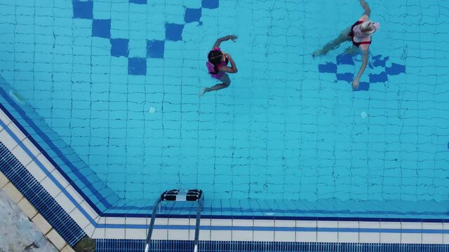 Beautiful woman with her daughter in swimming pool