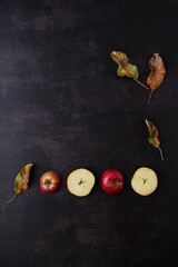 Flat lay creative concept of fallen autumn leaves and red apples on a dark background. Season concept. Happy Thanksgiving idea.