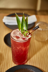 Long drink, red sweet drink with decoration of leaves and cinnamon. Preparation of a drink with white drink, alcohol, liquor.
