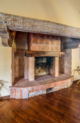 Rustic brick fireplace with antique wooden beam inside the house, interior decor concept.