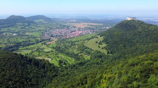 Aerial footage of flight over scenic landscape with forested hills and an old castle (Hohenneuffen) in the Swabian Alps in Southern Germany