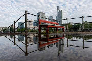 Fototapeta na wymiar Frankfurt, Germany - June 4, 2021: the famous red bench in front of the frankfurt skyline at the main riverfront in summer