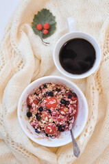 a plate of oatmeal with berries and cup of coffee