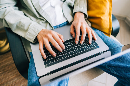 Young man mobile developer, programmer writes program code on a laptop computer in home office.