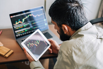 Caucasian businessman trading online, using computer technology, looking on stock exchange trade and analyzing