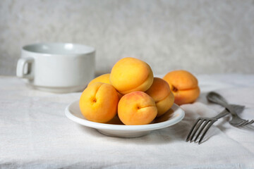 Naklejka na ściany i meble Ripe apricots on a white plate. Delicious vitamin fruit dessert on the table. Selective focus.