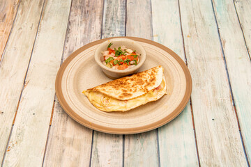 Mexican quesadilla with wheat tortilla stuffed with melted cheese and ham with pico de gallo and cilantro