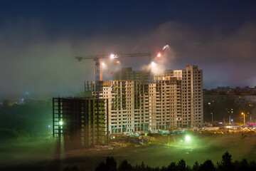 The construction of a multi-storey panel building, building site in the night fog