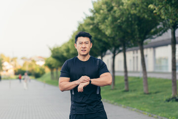 Male asian athlete, tired after a morning jog, runs in the park near the stadium