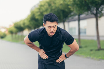 Male asian athlete having abdominal pain after fitness in park