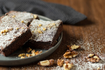 Selective focus on the front chocolate brownies with walnuts on wooden background, homemade bakery and dessert