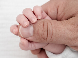 Newborn baby holding father’s finger