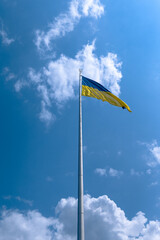 Ukrainian flag against the blue sky. The blue-yellow flag flutters in the wind 