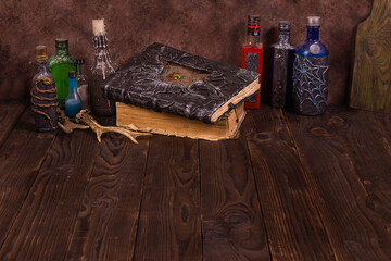 Closed old book with magic spells and a candle on the witch table. Occult, esotericism, divination and wicca concepts. Halloween vintage background, copy space.