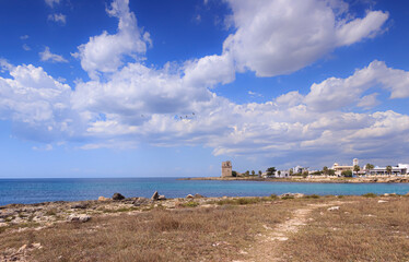 Obraz premium View of Torre Colimena town in Apulia region, Italy: the watchtower of the town is dominated by the flight of pink flamingos from the nearby Nature Reserve of Saline dei Monaci. 