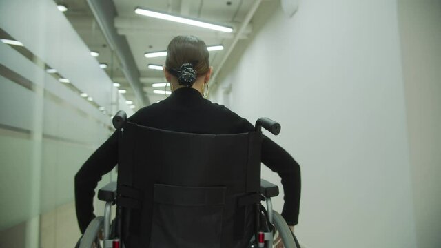 A young lady is riding a wheelchair through the office