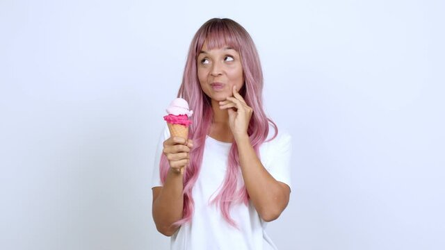 Young woman with pink hair holding a cornet ice cream standing and thinking an idea pointing the finger up over isolated background