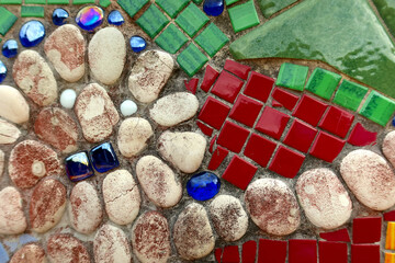 An abstract mosaic made up of colorful tiles and small pebbles