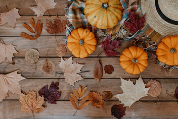 Flat Lay Autumn background decoration from dry leaves, straw hat and pumpkin on wooden background. Top view for Autumn, fall, Thanksgiving concept.