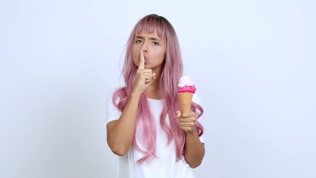 holding a cornet ice cream doing silence gesture over isolated background