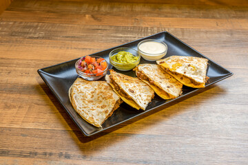 Mexican quesadillas stuffed with chili con carne and with pico de gallo, guacamole and cream cheese to dip