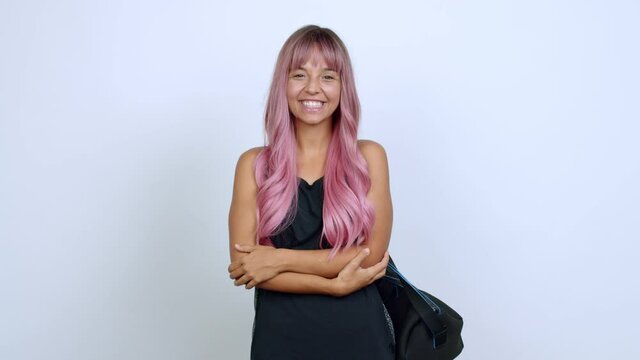 Young woman with pink hair with sport bag keeping the arms crossed while smiling over isolated background