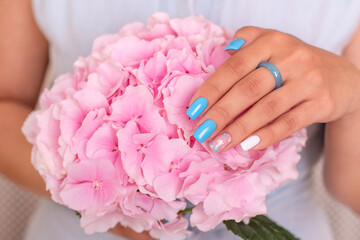 
Beautiful female hand with blue manicure nails holding hydrangea flower
