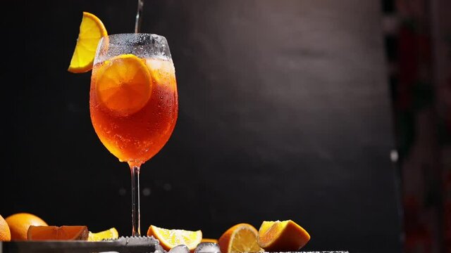 Aperol spritz with cocktail spoon. Cocktail aperol spritz with orange slices, ice and mint. Camera movement around the summer cocktail glass